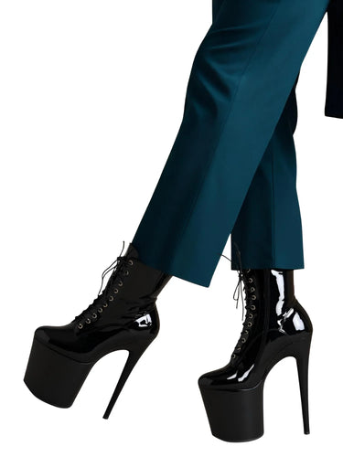 Black platform boots worn with teal pants on a white background